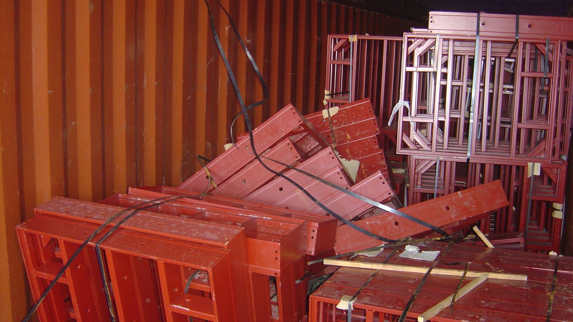 Inside a shipping container: steel frames shifted in transit, the stow collapsed.
